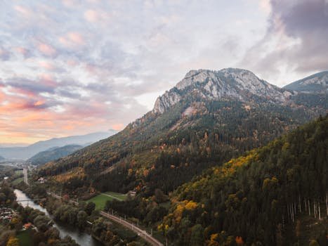 Stunning aerial shot of mountain scenery with autumn foliage at sunset, showcasing tranquil nature and vibrant colors.
