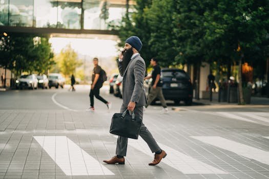 Confident Sikh businessman with briefcase crossing a city street in a suit and turban.