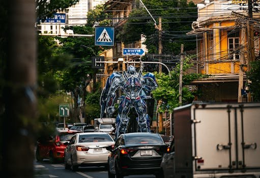 A towering robot statue stands amidst bustling traffic on a street in Bangkok, Thailand.