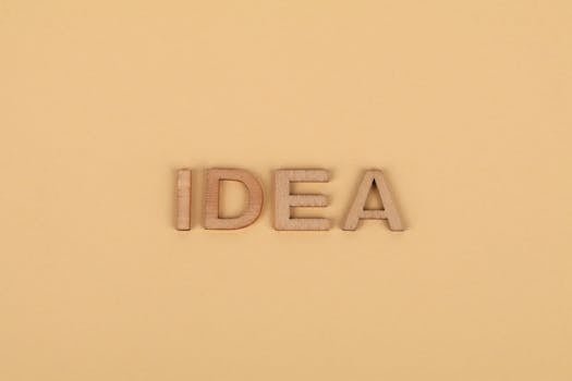 Wooden letters forming 'IDEA' on a plain beige surface, representing creativity.