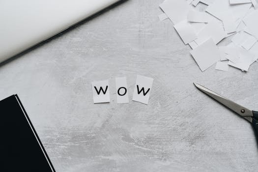 Crafted 'Wow' word with cutout letters, scissors, and paper for artistic projects.