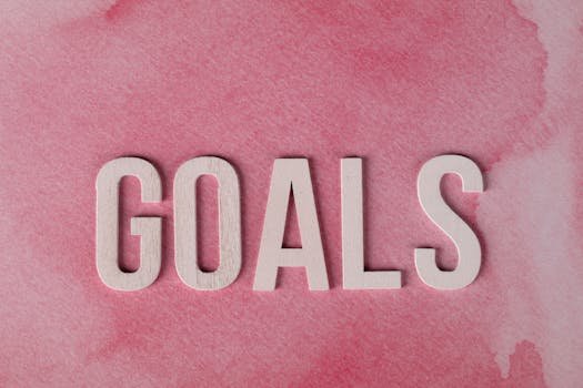 Motivational word 'GOALS' on a pink watercolor background for inspiration.