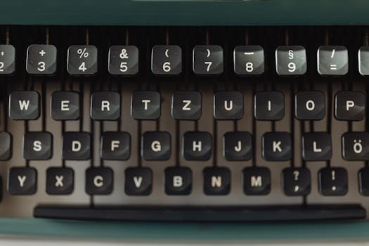 Close-up view of a black vintage typewriter keyboard with white keys showing letters and symbols.