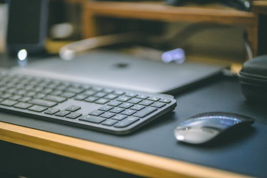 A sleek office setup featuring a wireless keyboard, mouse, and laptop on a desk.