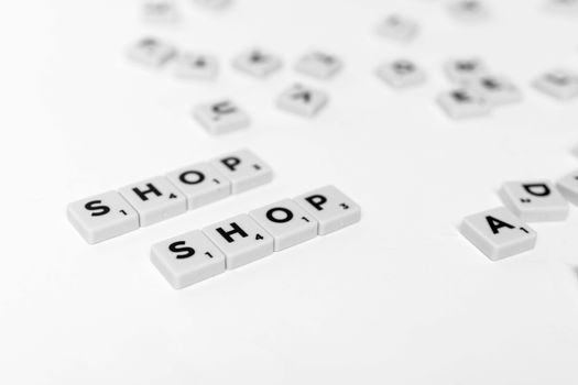 Close-up of scattered letter tiles spelling 'SHOP' on a clean white background.