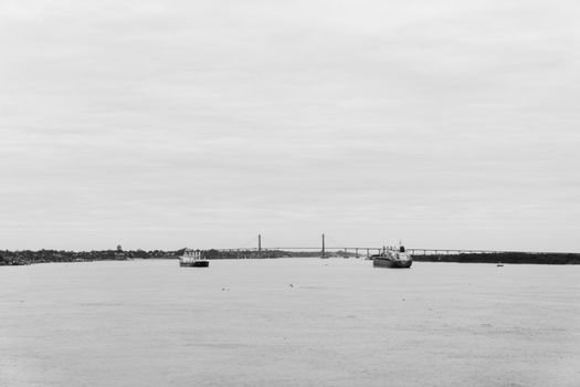 Black and white image of ships near Rosario-Victoria Bridge on Parana River.