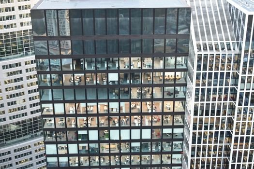 High-rise building facade with visible office interiors, showcasing urban architecture.