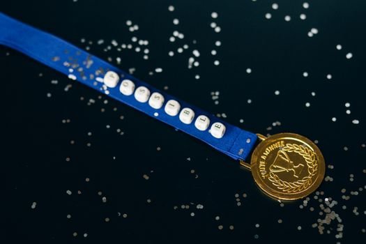 Close-up of a gold medal on a blue ribbon with 'possible' beading, symbolizing achievement.