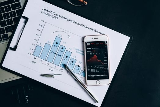 A smartphone displaying stock data rests on a financial report graph.