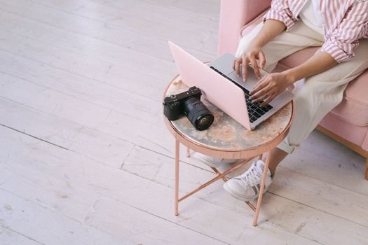 An adult using a laptop at home, with a camera on a round table, showcasing a work-from-home setting.